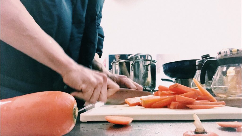 まな板の上で人参を包丁で切る